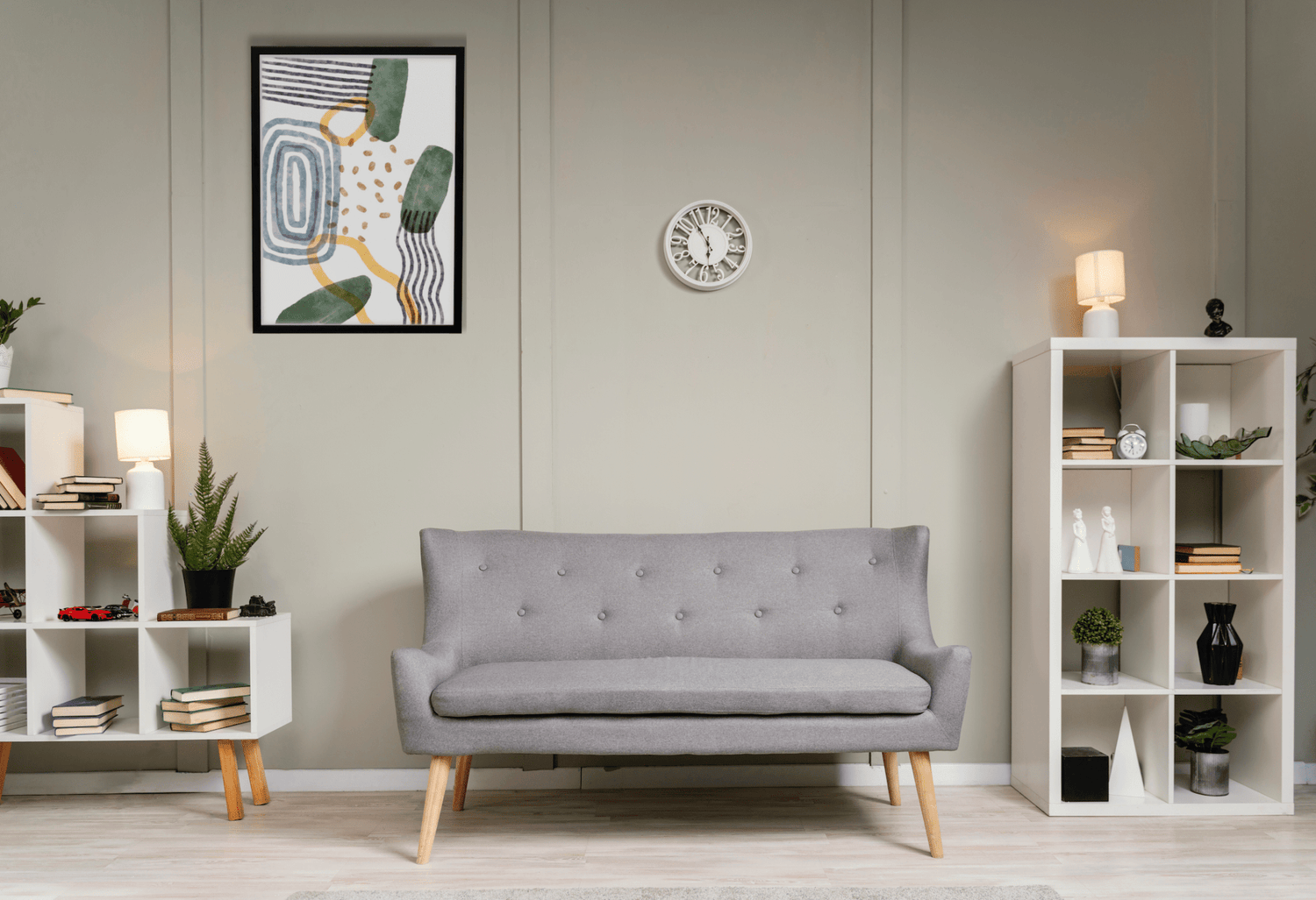 Salon moderne avec un canapé gris, des étagères blanches et une œuvre d'art murale contemporaine