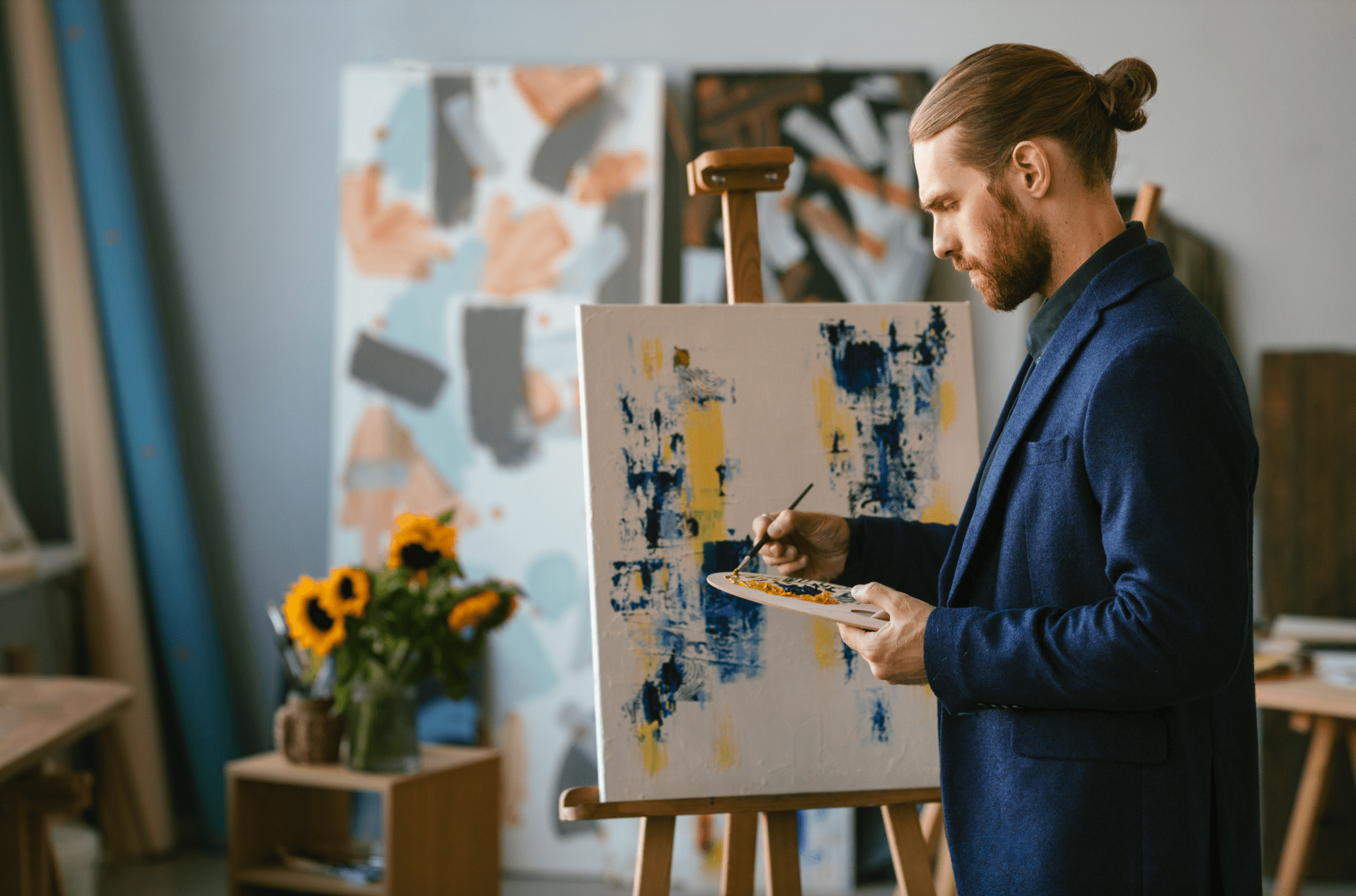 Artiste peignant sur toile avec palette, dans un studio créatif rempli de œuvres colorées