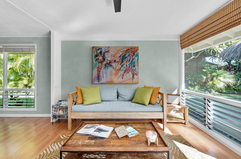 Salon moderne avec canapé en bois, coussins colorés et tableau artistique au mur