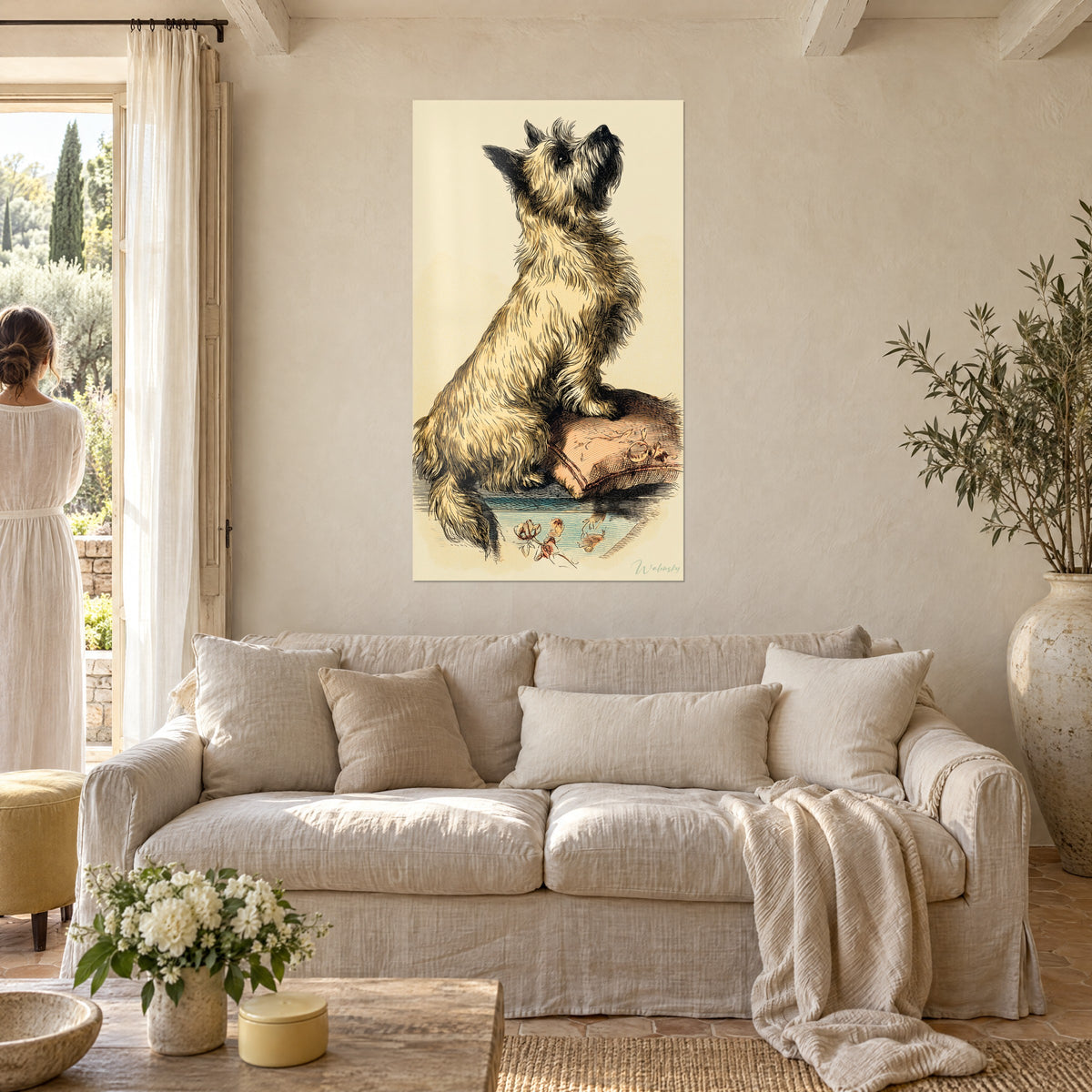 Cuadro cairn terrier de pelo beige hirsuto, hocico levantado, cojín rosa salmón; mujer de espaldas sobre un sofá en un salón luminoso