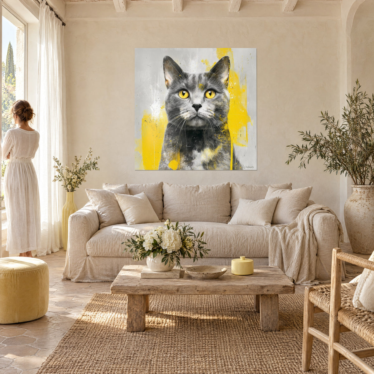 Quadro Gatto grigio dagli occhi dorati schizzato di giallo vivo, di fronte a una donna di spalle, sopra un divano in un soggiorno luminoso