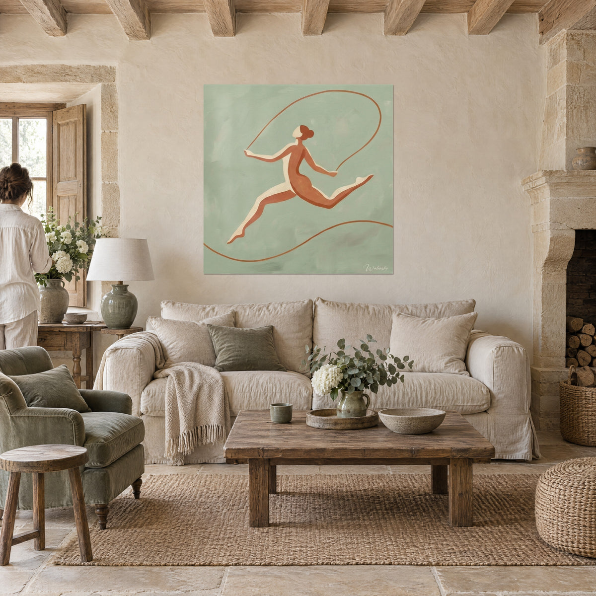 Quadro di una ginnasta che salta in ocra, corda color rame annodata su sfondo verde salvia, persona di spalle, sopra un divano in un soggiorno luminoso