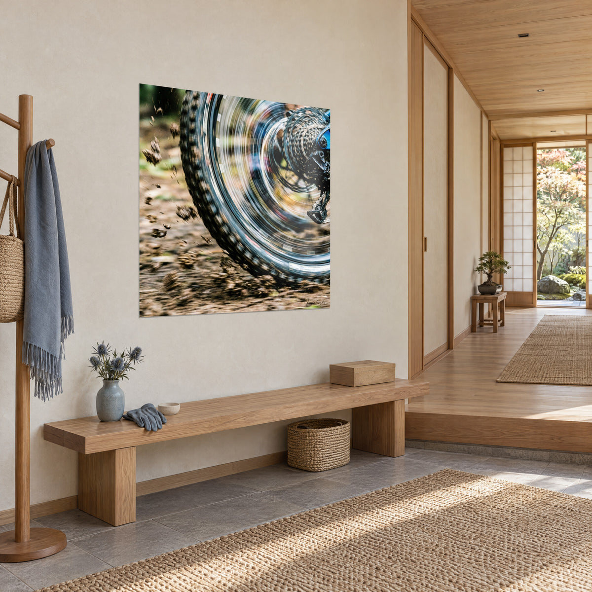 Wall art of a mountain bike rear wheel in rotating motion blur, silver cogs and ochre mud, hung near a japandi entryway