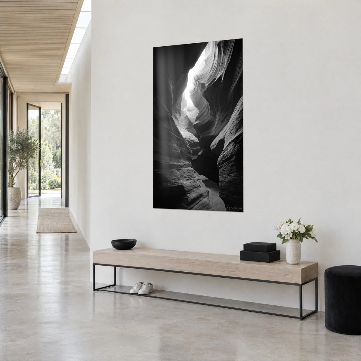 Schilderij smalle kloof met golvende lagen, diep zwart en stralend wit, driekwart zicht op een witte muur boven een houten bank