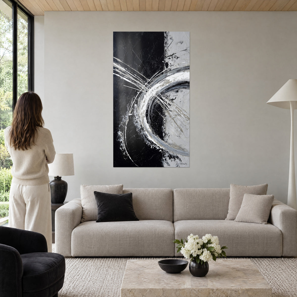 Quadro con un cerchio bianco argentato che attraversa uno sfondo nero opaco, schizzi e linee sottili, sopra un divano in un soggiorno luminoso