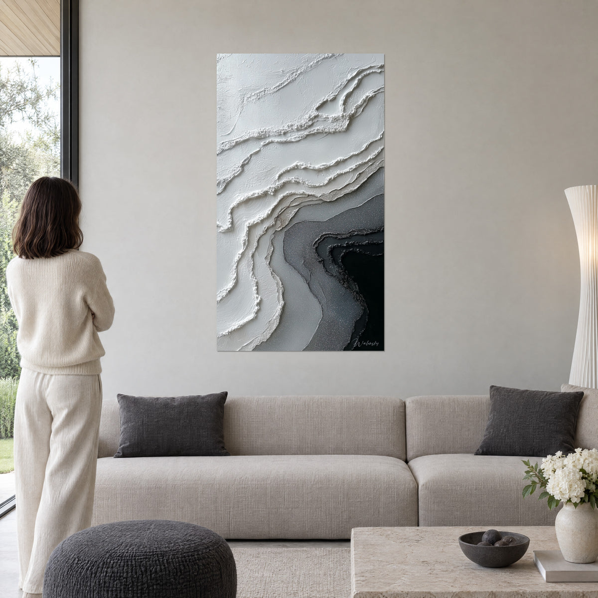 Quadro astratto con onde di pasta bianca che sfumano verso un nero profondo e grigio perla, sopra un divano in un soggiorno luminoso