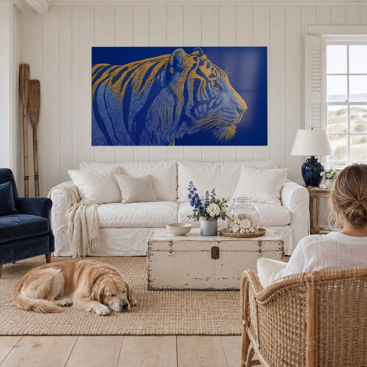 Quadro tigre a righe dorate su fondo blu notte, osservato da una donna di spalle e dal suo retriever, sopra un divano in un soggiorno luminoso