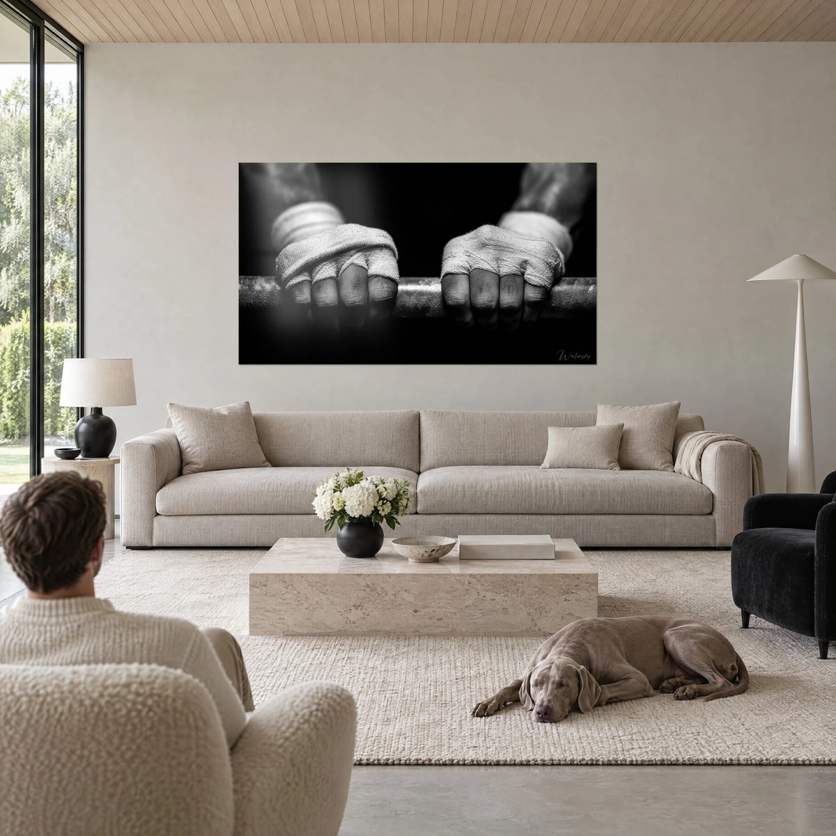 Wall art bandaged hands gripping a steel bar, grey stripes on deep black background, above a sofa in a bright living room