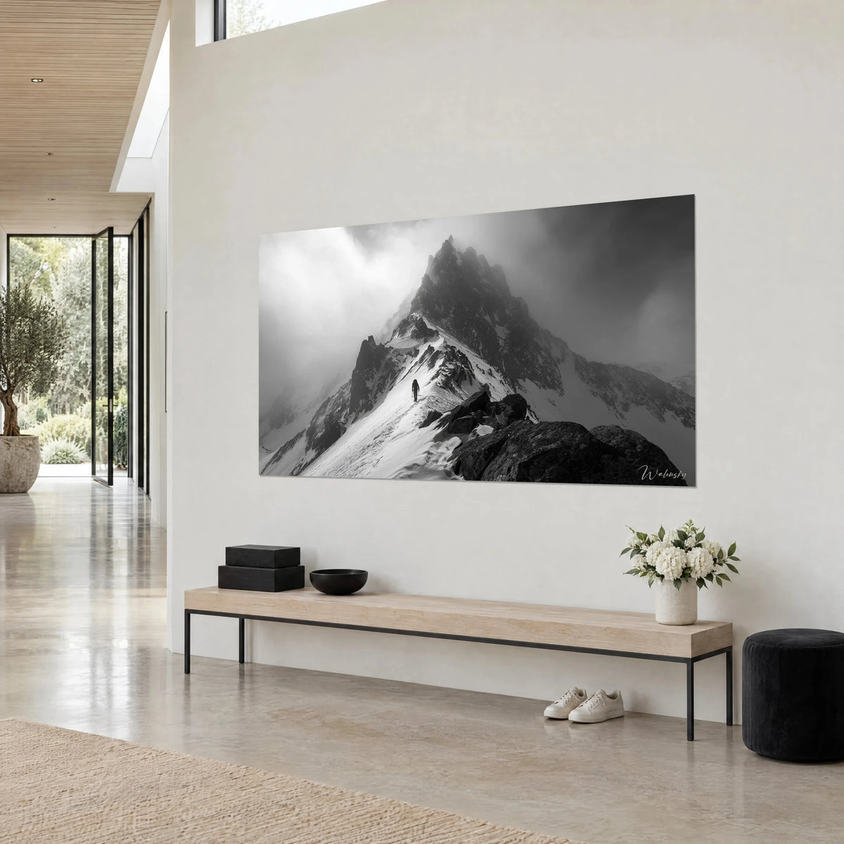 Tableau cime rocheuse dans les nuages, neige blanche et roche anthracite, vu de trois-quarts, au-dessus d'un banc de bois dans un séjour
