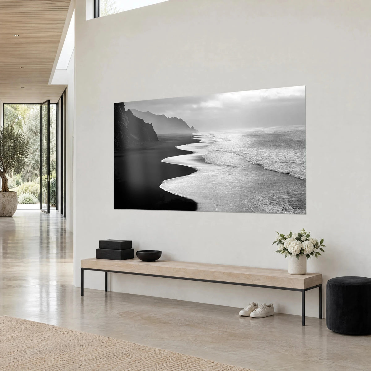Tableau rivage volcanique en noir et blanc, langue d'écume blanche sinueuse sur sable d'ébène, accroché dans une maison d'architecte
