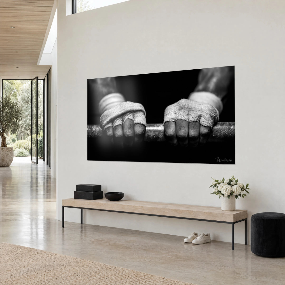 Wall art weightlifter's fists wrapped in grey gauze, ridged metal bar, black background, on a white wall seen three-quarter view
