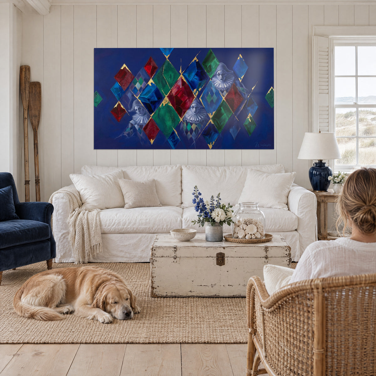 Gemälde Geisterhafte Pierrots und Rauten in Rot, Grün und Blau mit Goldfäden, über einem Sofa in einem hellen Wohnzimmer