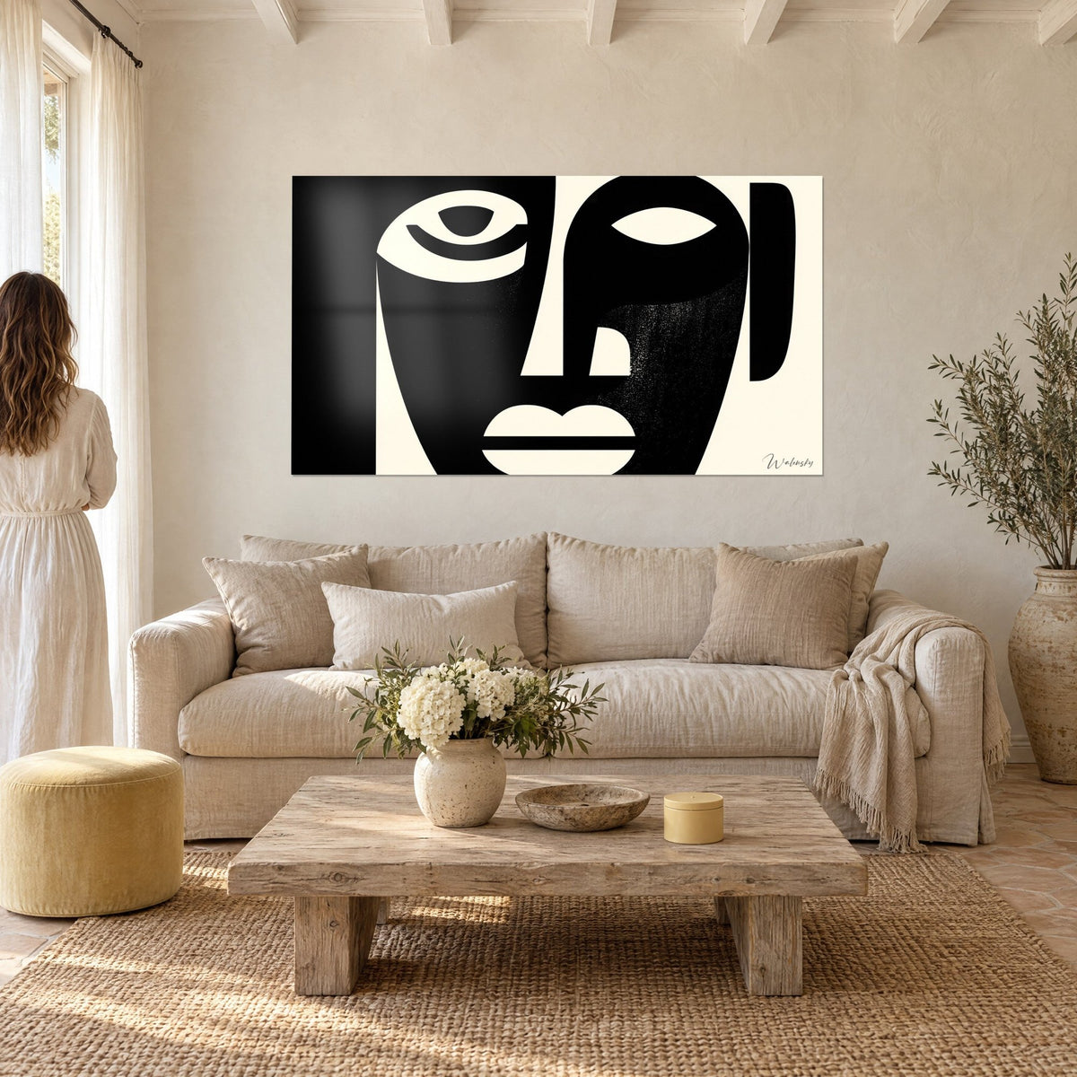 Tableau masque africain stylisé noir et ivoire, œil en croissant, lèvres pleines, au-dessus d'un canapé dans un salon lumineux