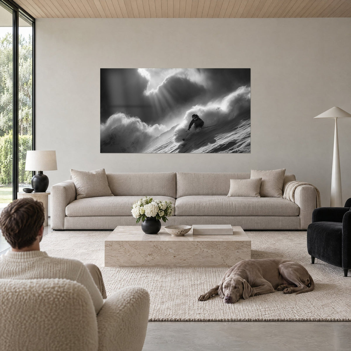Gemälde eines Skifahrers in einer Pulverschneewolke in Schwarzweiß, Sonnenstrahlen durchbrechen die Wolken, über einem Sofa in einem hellen Wohnzimmer