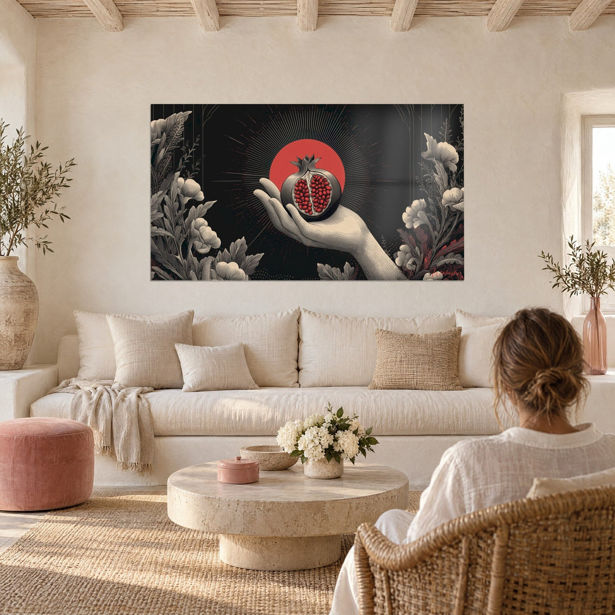 Tableau main ouverte offrant une grenade rouge sur disque corail, fond noir, pivoines grises, au-dessus d'un canapé dans un salon lumineux