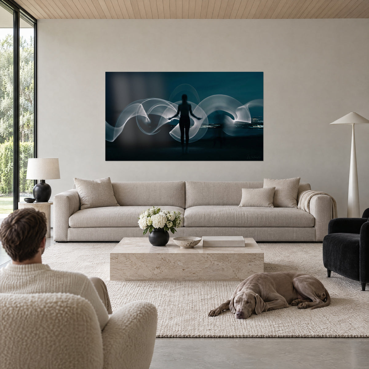 Tableau silhouette noire entourée de rubans lumineux blancs sur fond bleu nuit, bras écartés, au-dessus d'un canapé dans un salon lumineux