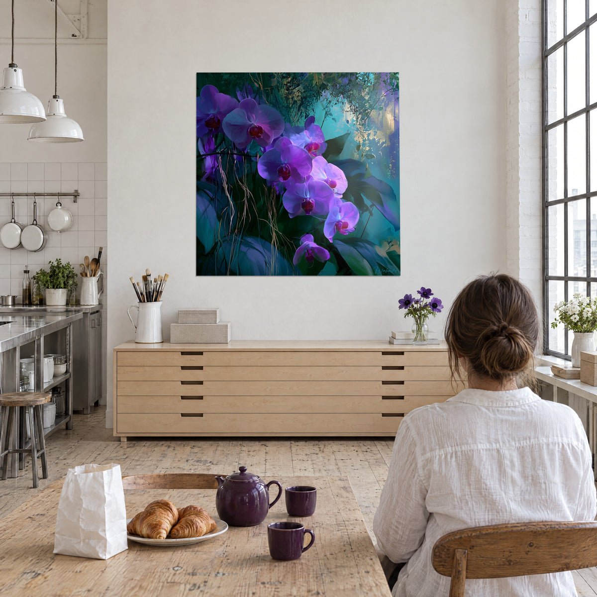 Cuadro de una floración de orquídeas lilas con corazón carmesí, hojas verde abeto y azul petróleo, mujer de espaldas junto a una cocina de loft