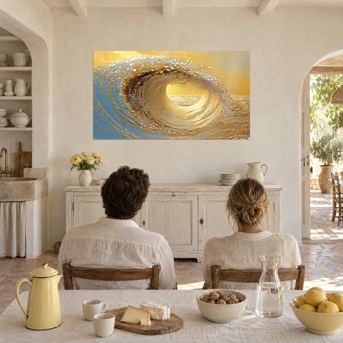 Cuadro ola de mar en oro líquido, gotas ámbar y reflejos azules, frente a una pareja sentada de espaldas a la mesa de un mas provenzal