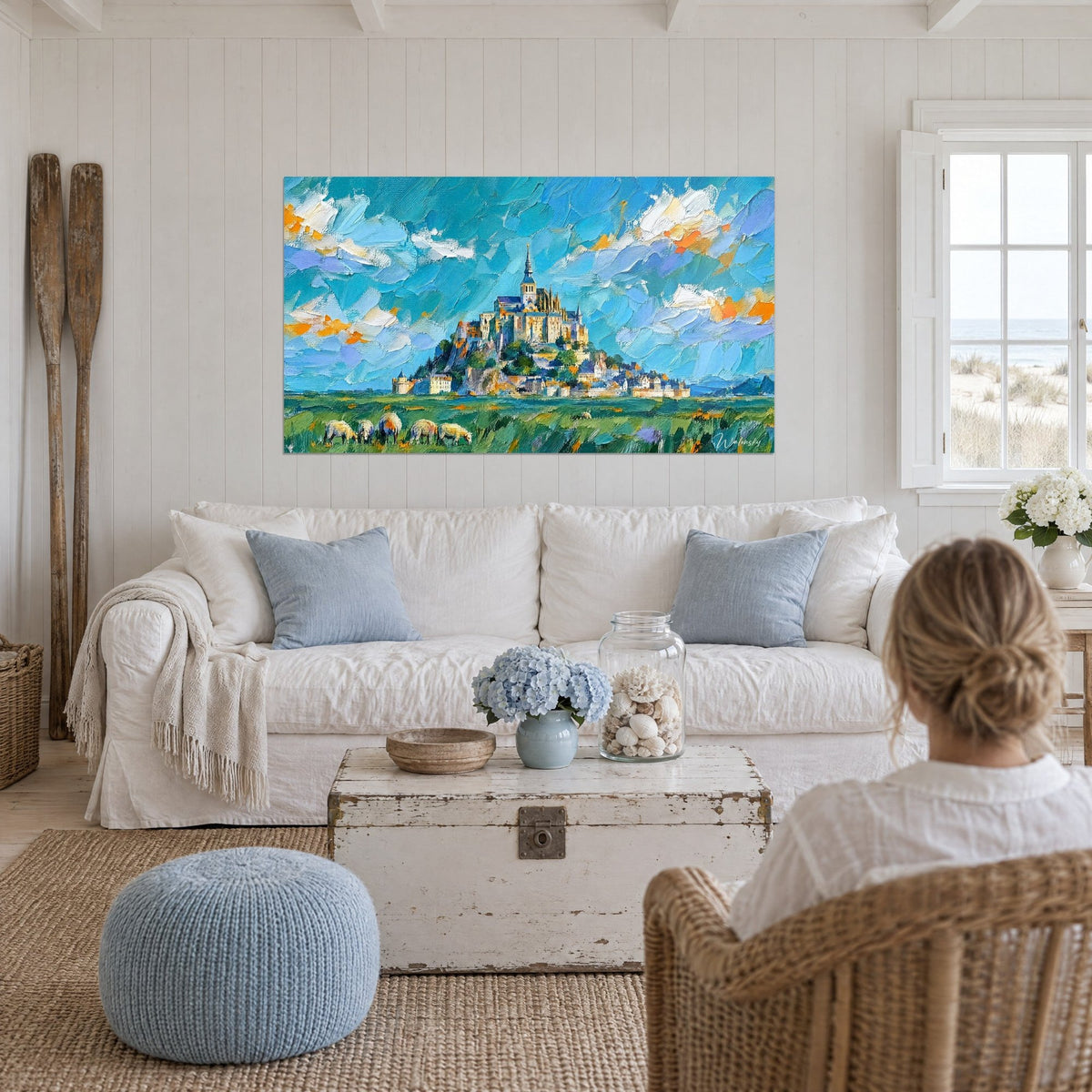 Schilderij van de versterkte abdij op haar rots, turquoise lucht met oranje wolken, boven een bank in een lichte woonkamer