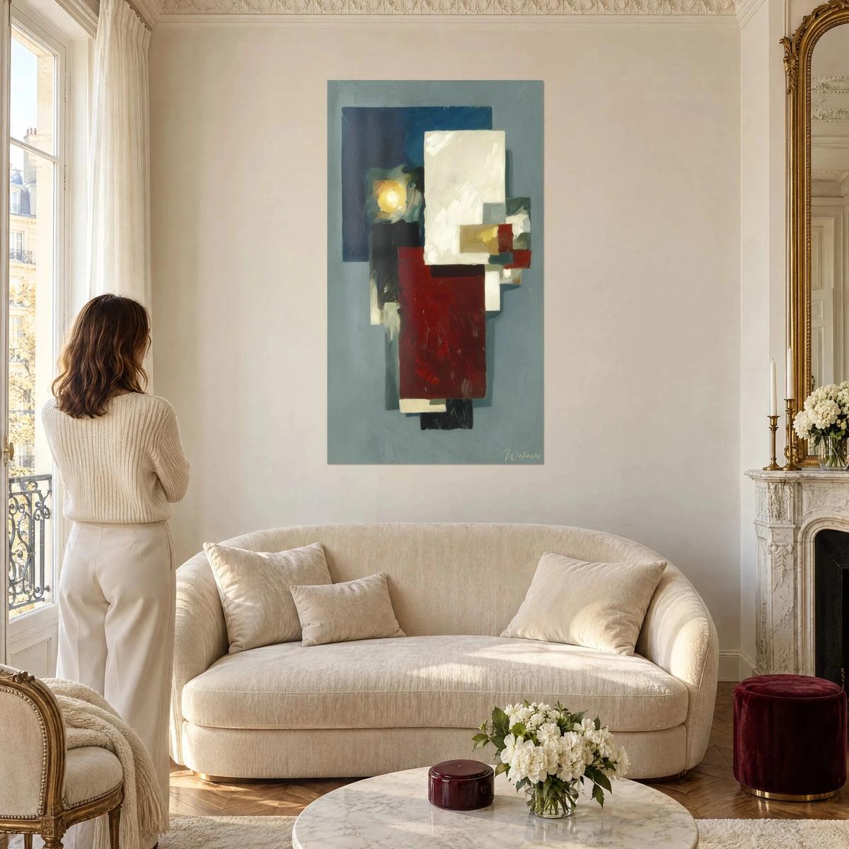Tableau abstrait de blocs rouge bordeaux et blanc crème sur fond bleu nuit, femme de dos, au-dessus d'un canapé dans un salon lumineux