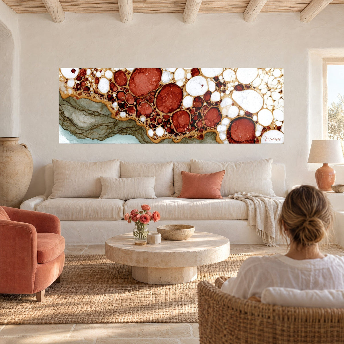 Cuadro con celdas rojo terracota bordeadas de oro sobre fondo blanco, cinta salvia a la izquierda, sobre un sofá en un salón luminoso
