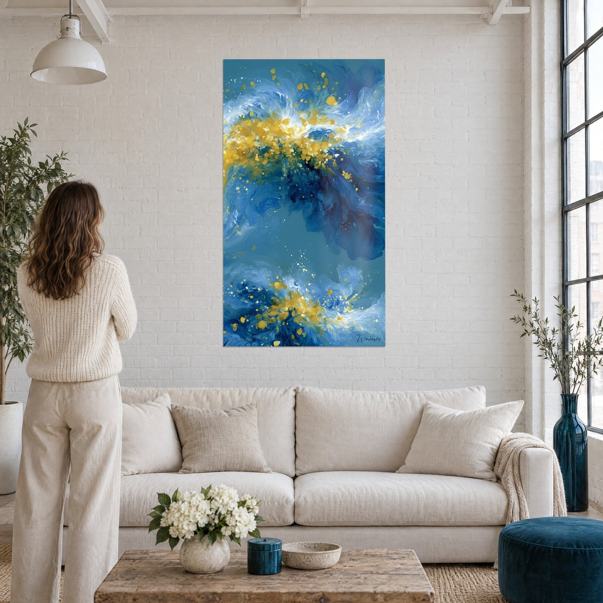 Tableau vagues bleu marine aux éclats dorés, écume blanche et or, femme de dos, au-dessus d'un canapé dans un salon lumineux