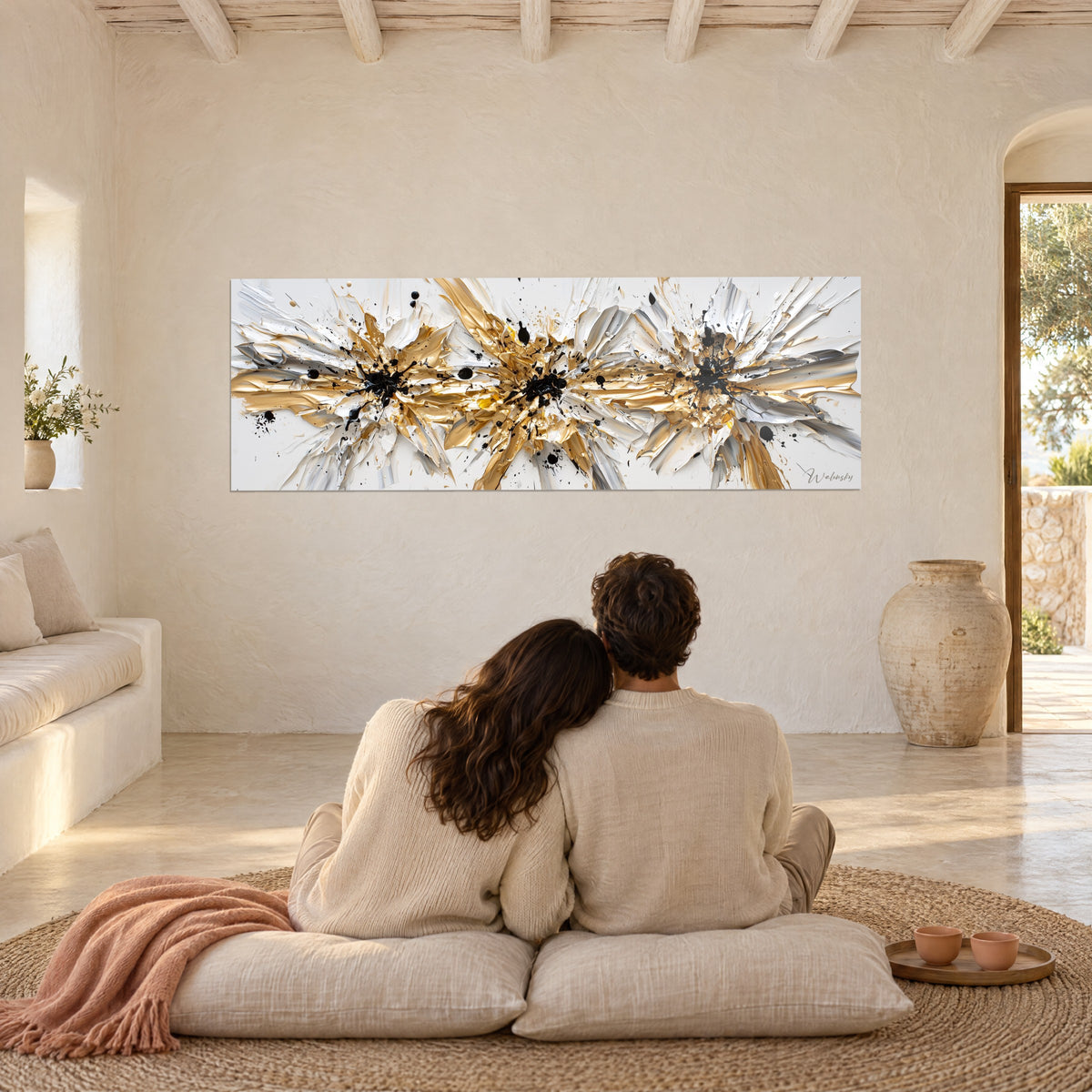 Schilderij uitbarsting van gouden en zilveren pigmenten, met het paletmes gestreepte pasta, tegenover een stel dat op kussens zit