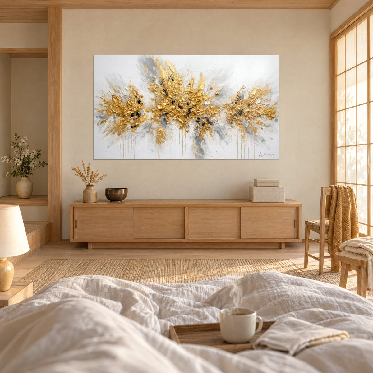 Cuadro con floración metálica dorada y gris sobre fondo blanco, materia gruesa y chorreados, persona de espaldas, encima de una cama en un dormitorio luminoso