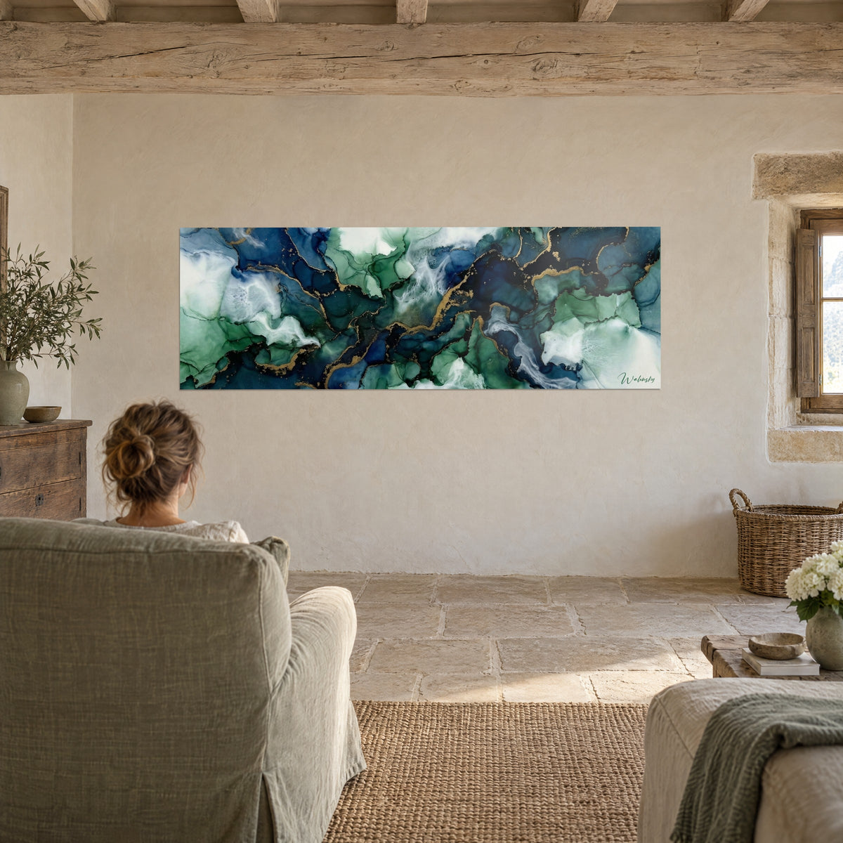 Tableau paysage liquide abstrait marine et émeraude, coulures blanches et or, face à un fauteuil dans un salon en pierre
