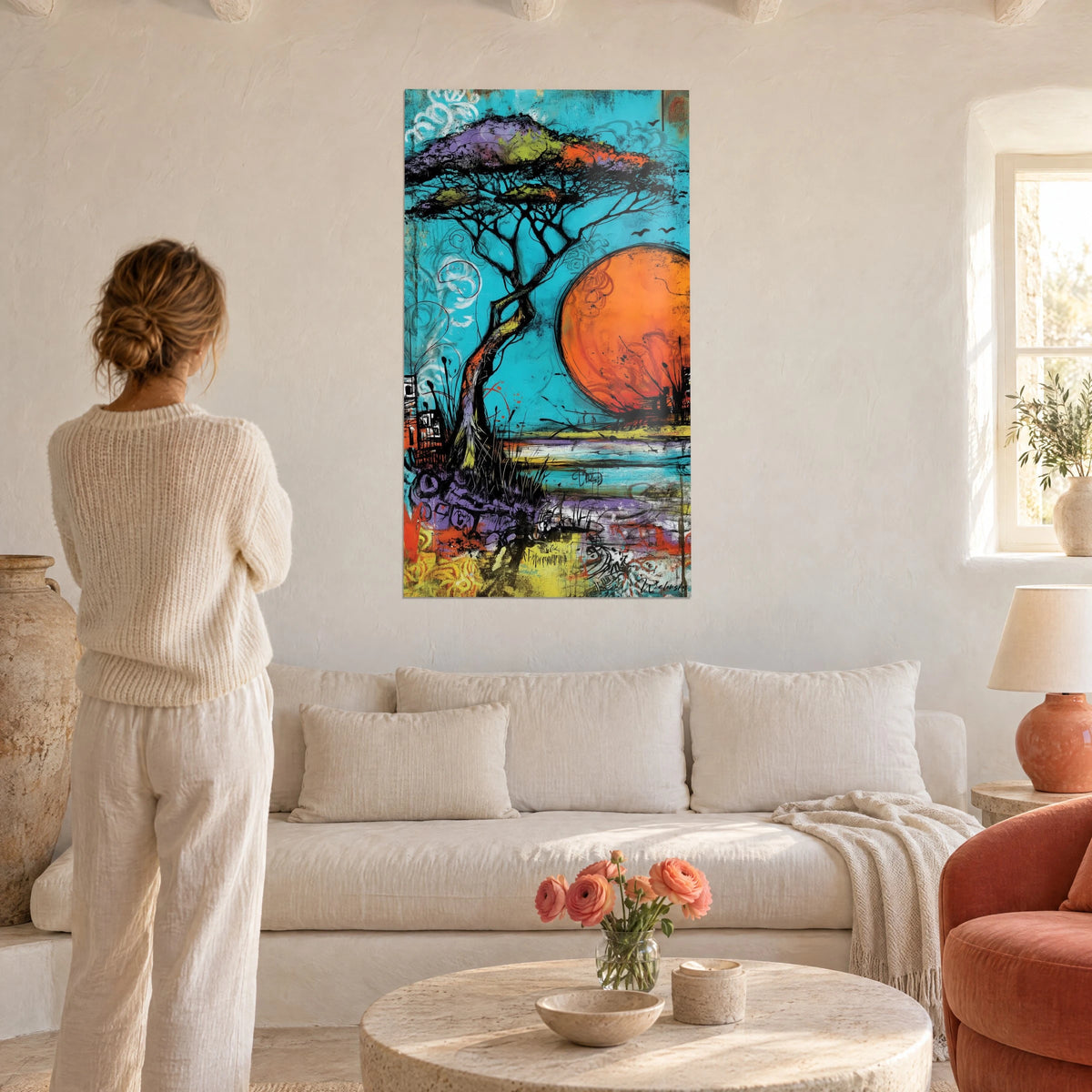 Tableau acacia aux ramures noires sous un soleil orange, fond turquoise et violet, femme de dos au-dessus d'un canapé dans un salon lumineux