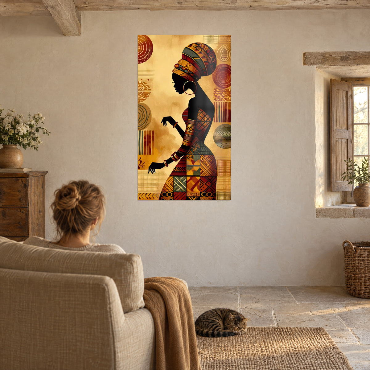 Tableau beauté africaine au turban sculpté ambre et rouge, robe aux carrés tribaux, personne de dos et chat tabby sur le fauteuil