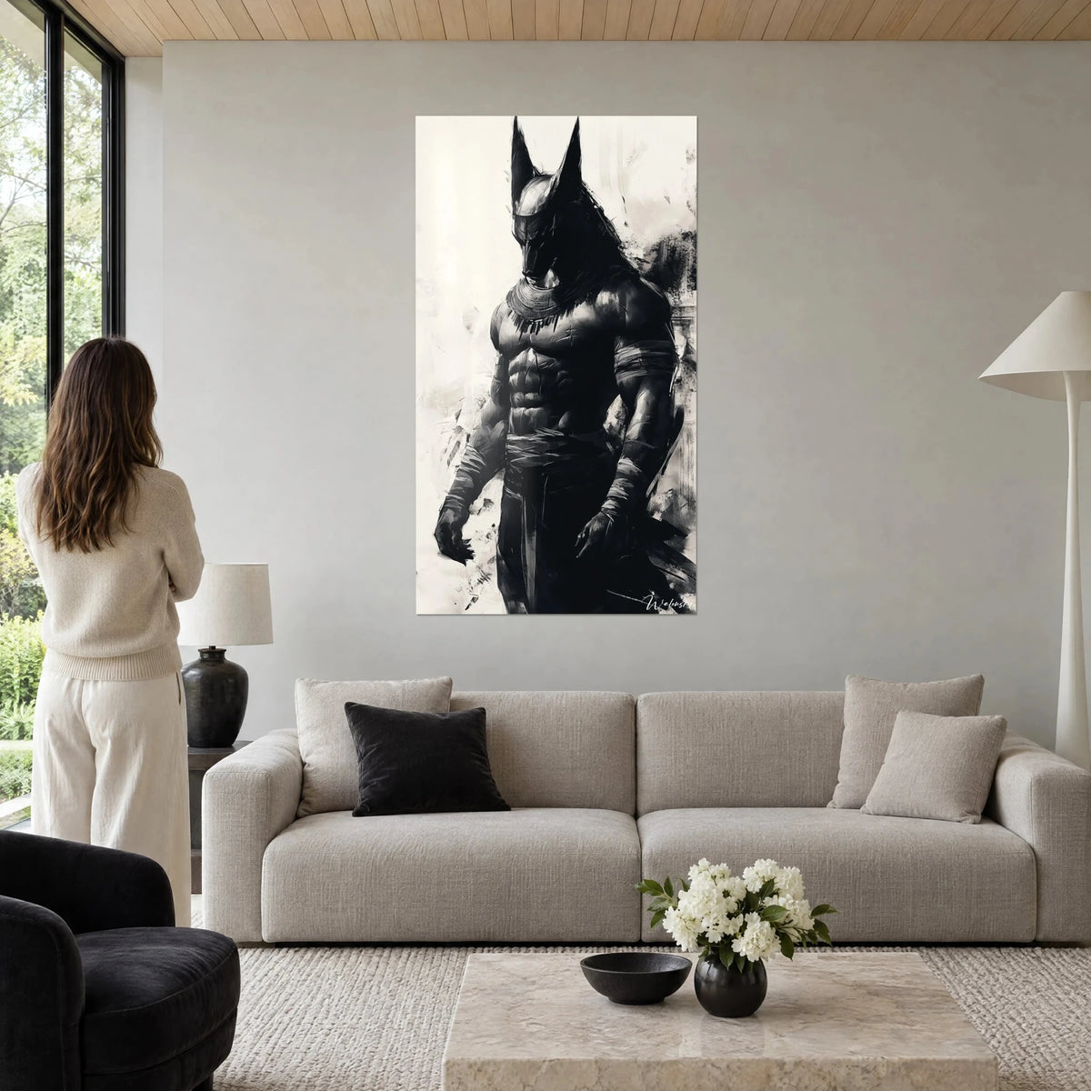 Quadro Anubi in inchiostro nero su fondo avorio, torso scolpito e orecchie dritte, donna di spalle, sopra un divano in un soggiorno luminoso
