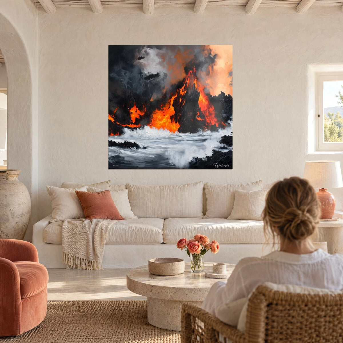 Tableau volcan en éruption crachant des flammes orange sur mer blanche et basalte noir, femme de dos, au-dessus d'un canapé dans un salon lumineux