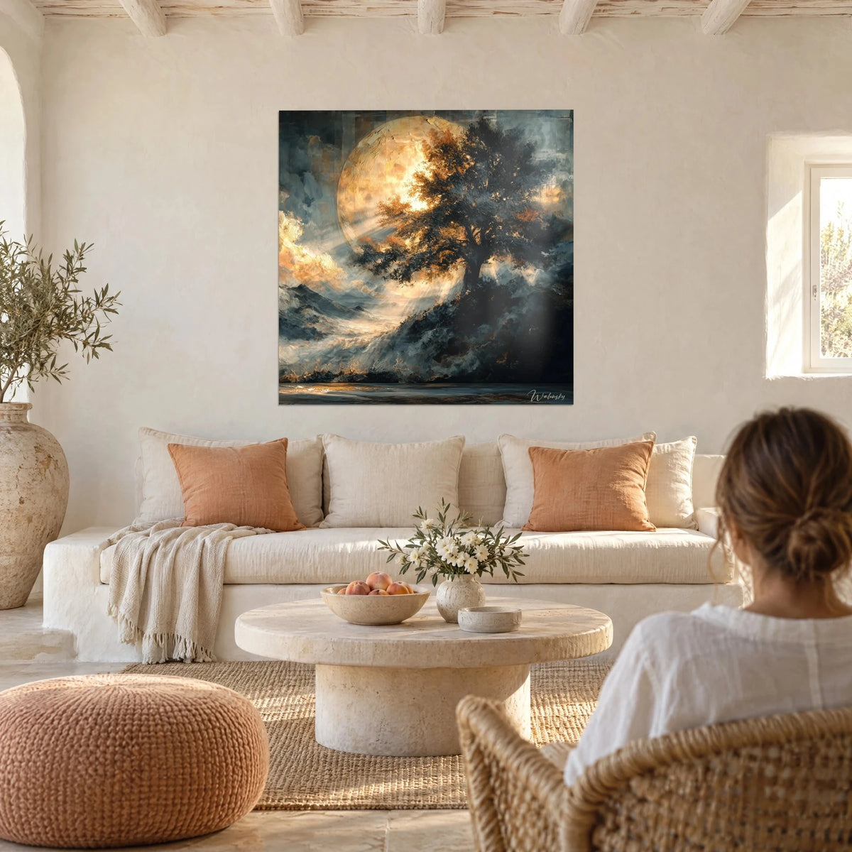 Wall art gnarled oak tree in front of a golden moon against a midnight blue sky, a woman seen from behind, above a sofa in a bright living room