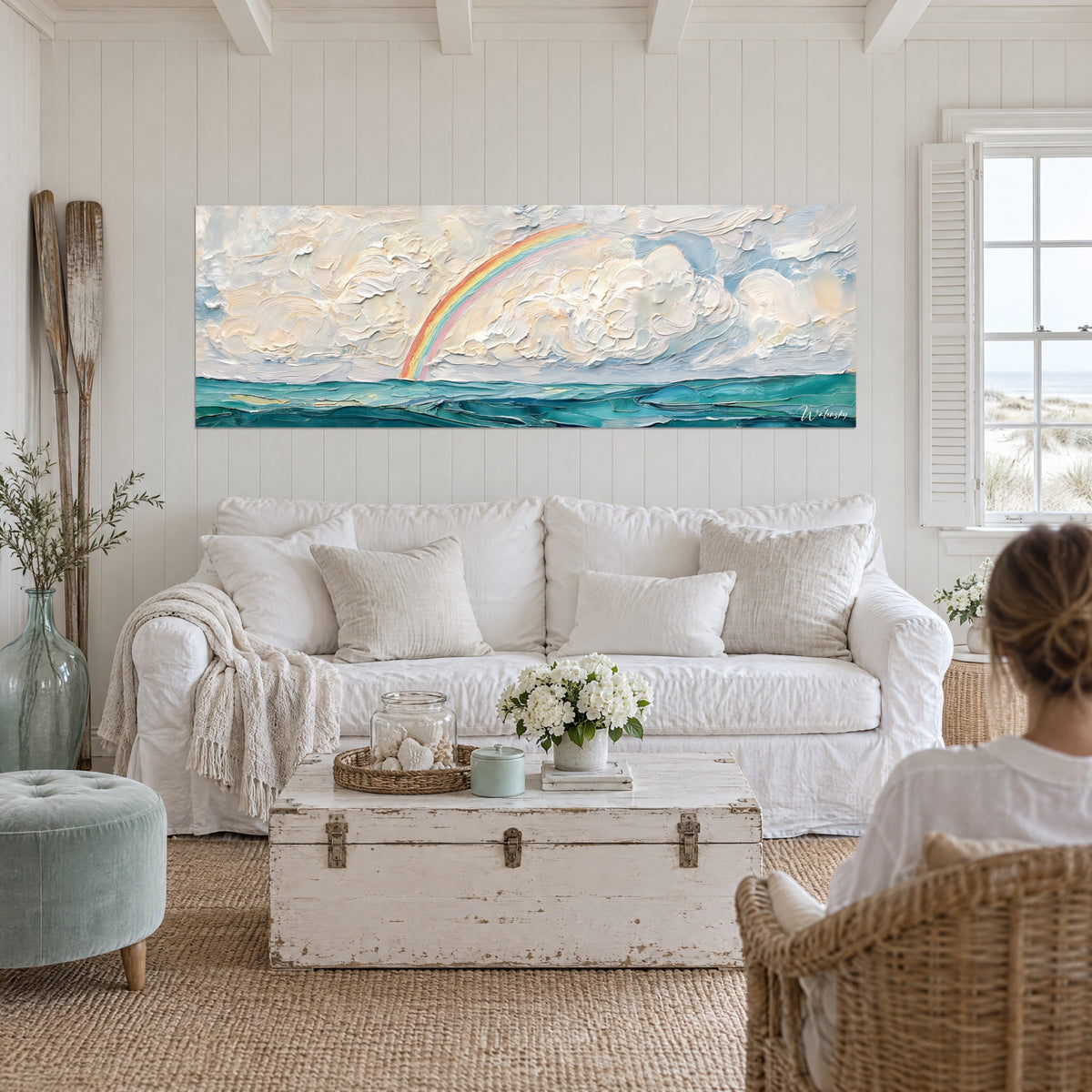 Mer turquoise et ciel nuageux crème traversés d'un arc-en-ciel doux, accrochés au-dessus d'un lit dans une chambre claire