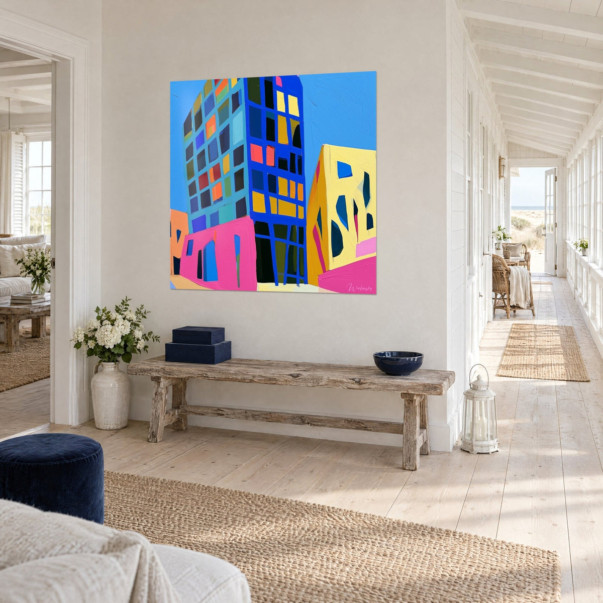 Tableau gratte-ciel cubiste en peinture épaisse, ciel azur, bloc jaune paille et base rose, au bord d'un couloir clair