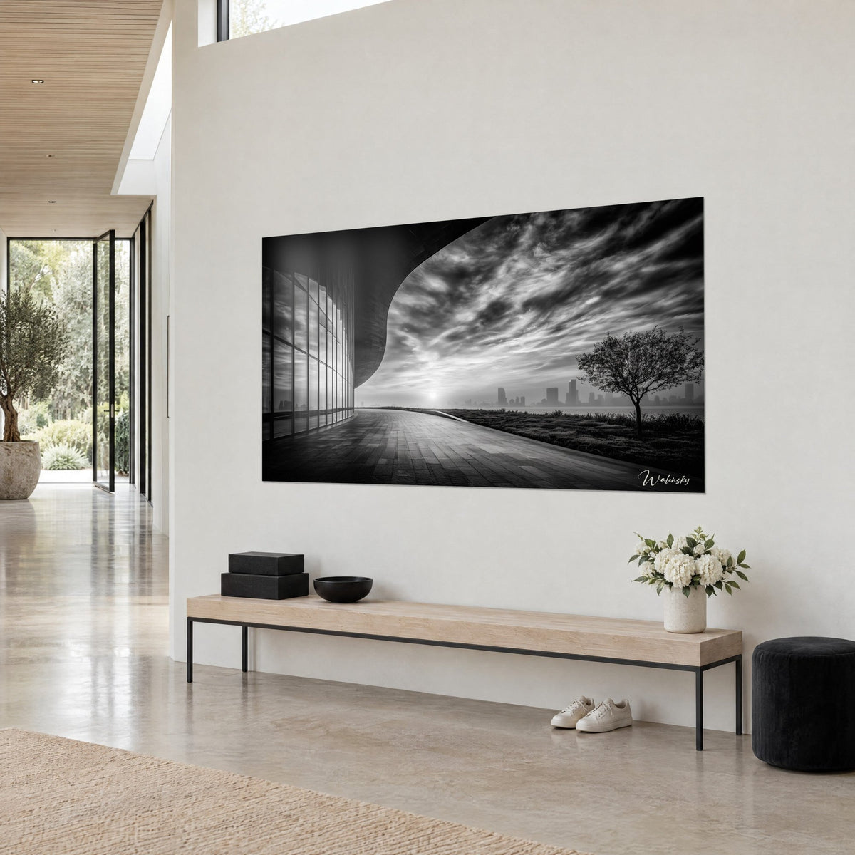 Tableau promenade dallée longeant un mur courbe gris anthracite, soleil blanc voilé, arbre noir, salon d'architecte