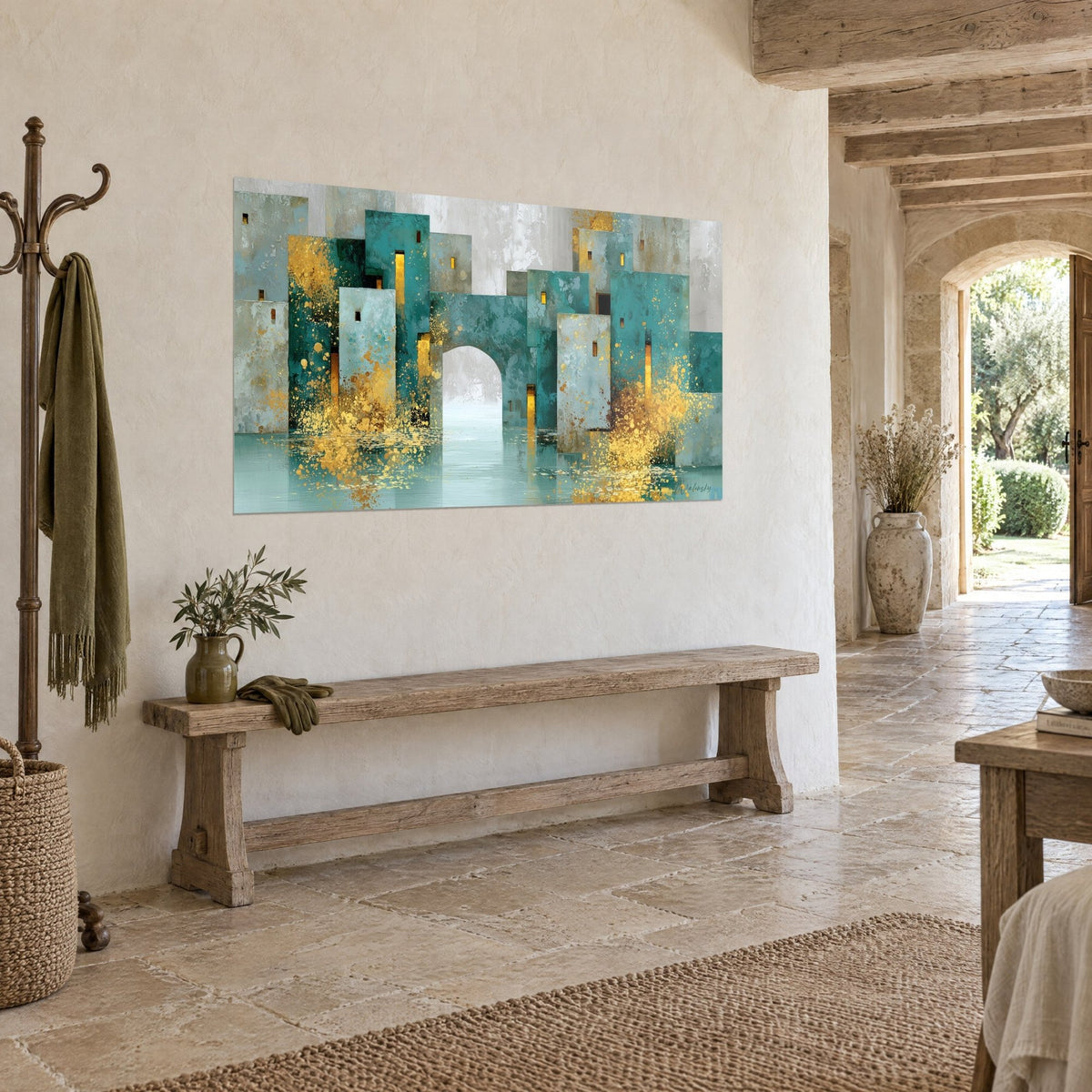 Tableau village cubique turquoise et ocre percé d'une grande arche, fenêtres ambrées, accroché sur un mur crépi beige, banc en bois