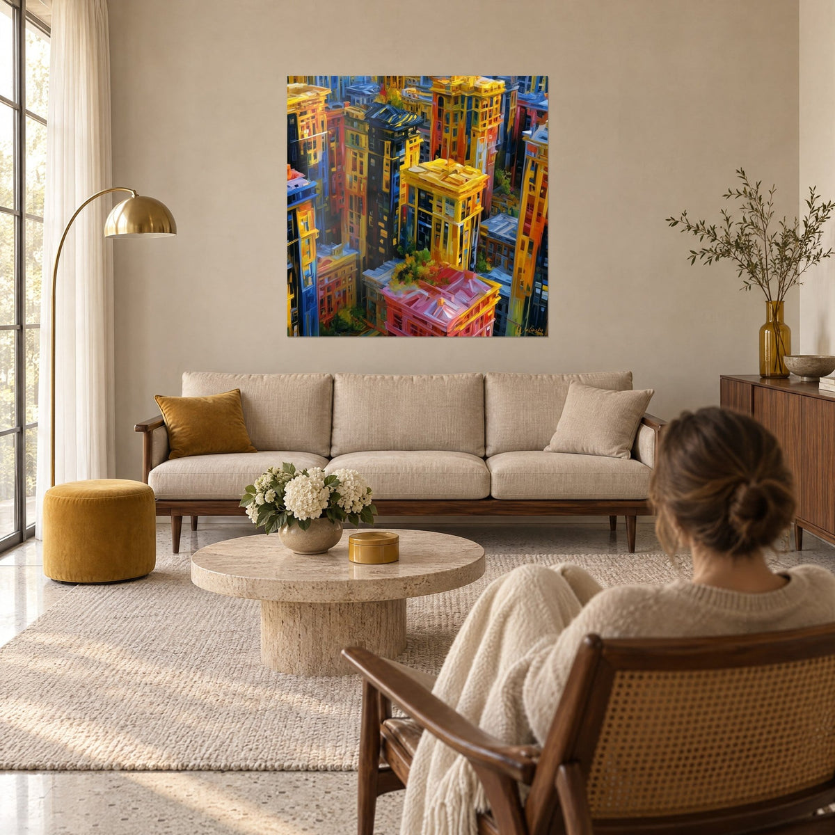 Tableau gratte-ciel dorés en vue plongeante, façades jaune safran et bleu nuit, femme de dos, au-dessus d'un canapé dans un salon lumineux