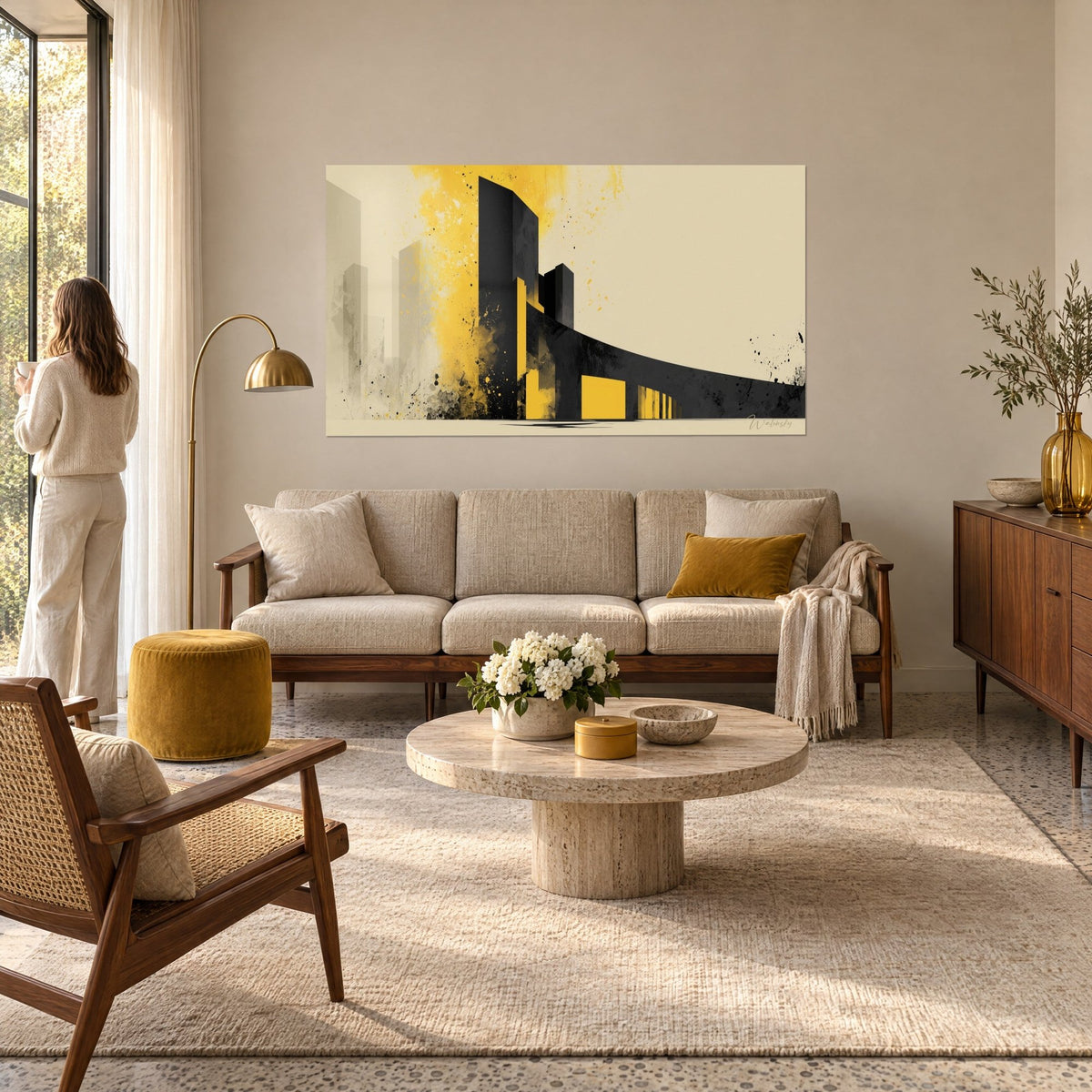 Quadro torre nera con schizzi giallo senape su fondo crema, una donna di spalle, sopra un divano in un soggiorno luminoso