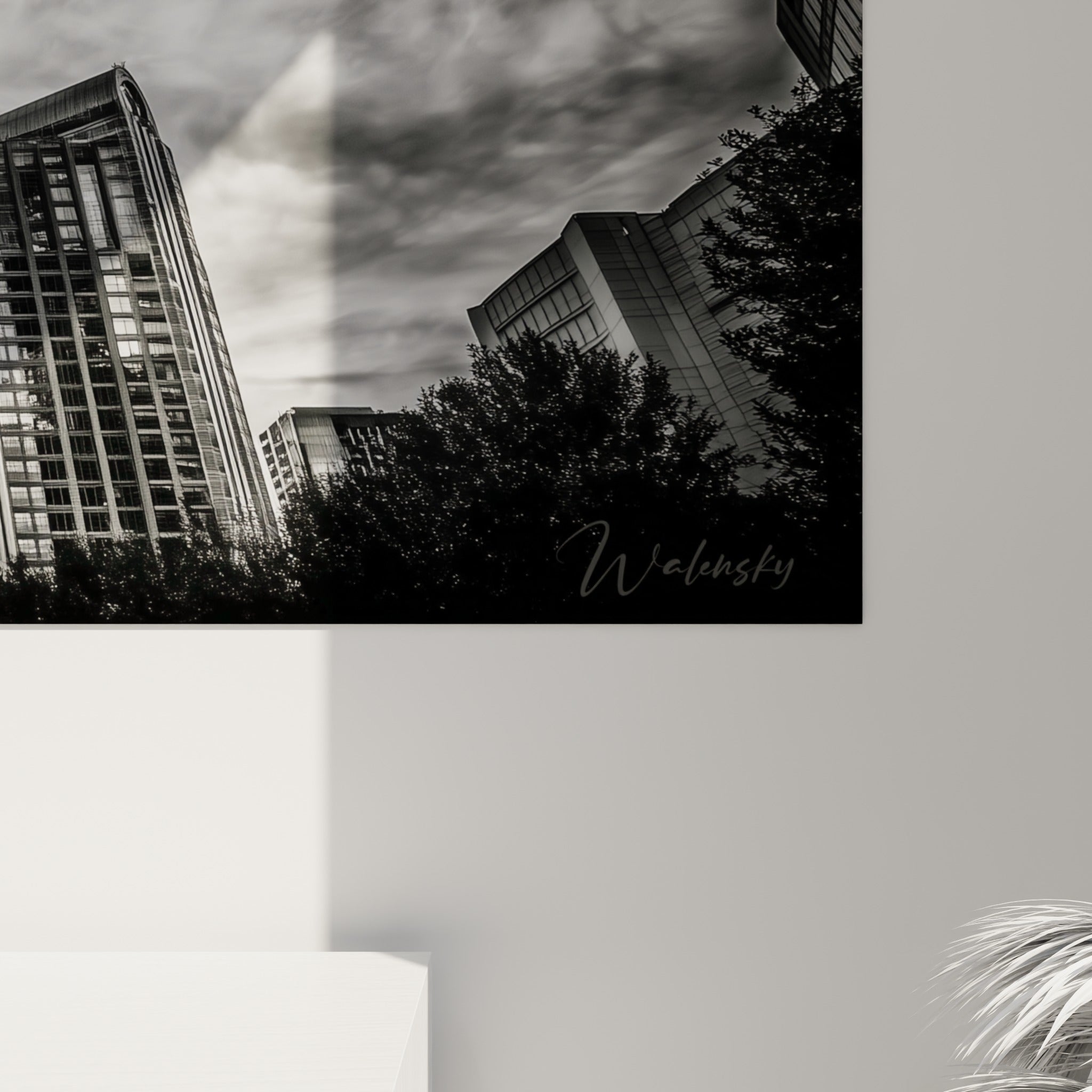 Détail du grain photographique noir et blanc, façade vitrée grise et nuages étirés en gros plan sur l'œuvre encadrée