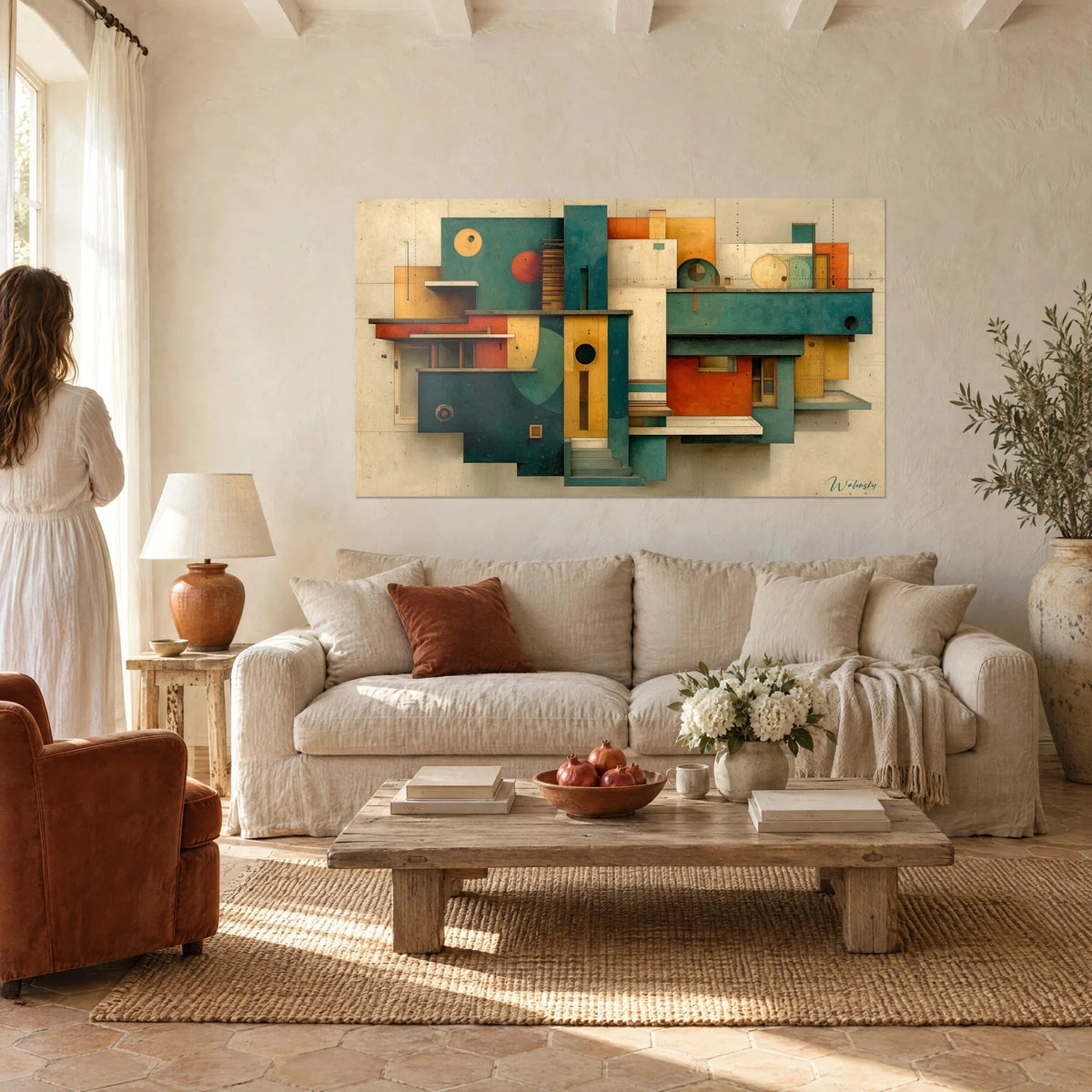 Tableau maisons cubistes en teal et ocre, volumes entrelacés, regardé par une femme de dos au-dessus d'un canapé dans un salon lumineux