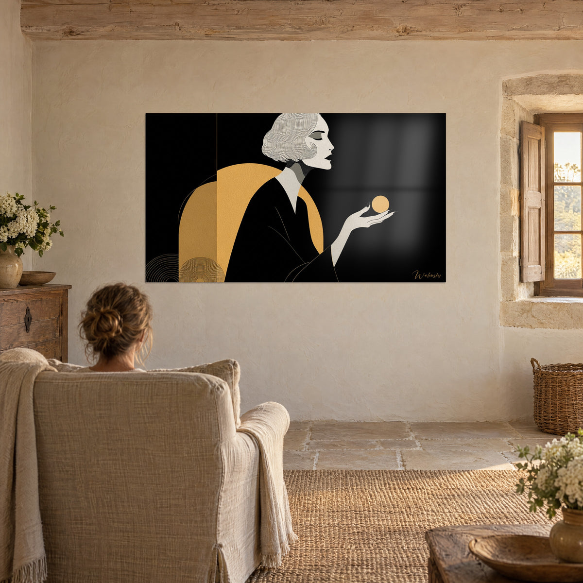 Cuadro perfil de mujer con párpados cerrados y esfera dorada en la mano, negro y ocre, frente a un sillón de lino en un salón de piedra