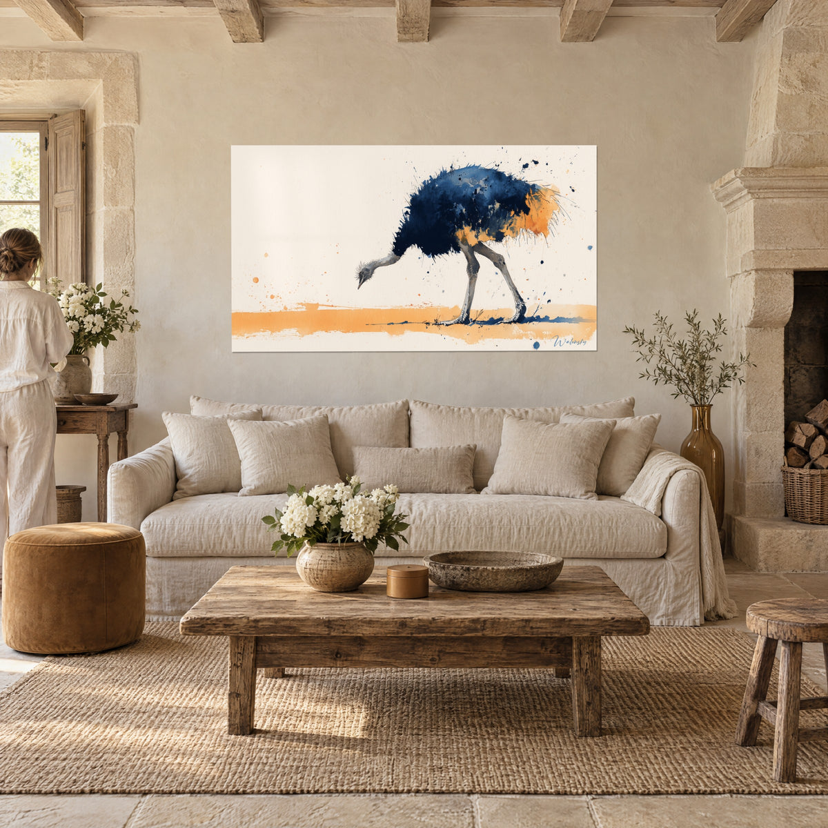 Cuadro avestruz de plumaje azul marino salpicado de ocre, cuello inclinado, una persona de espaldas, sobre un sofá en un salón luminoso