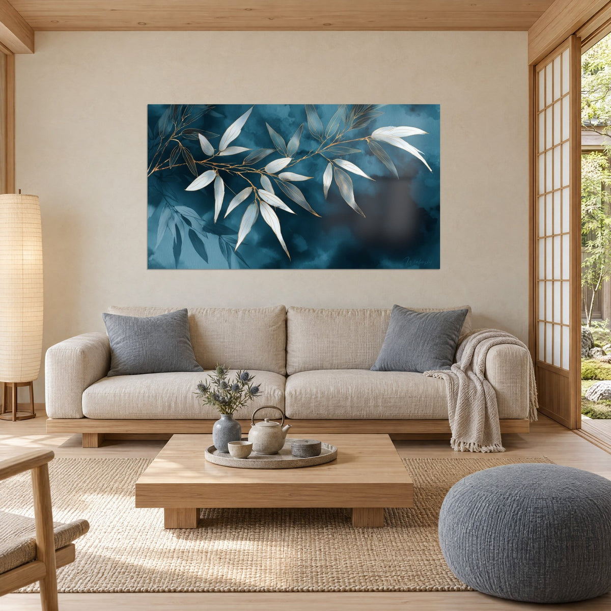 Tableau branche de bambou aux feuilles ivoire nacrées sur fond bleu nuit, nervures dorées, au-dessus d'un canapé dans un salon lumineux