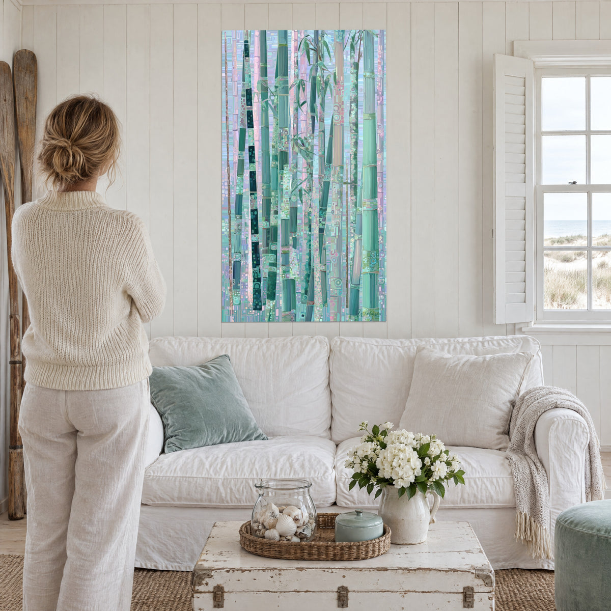 Wall art bamboo grove in mint green and pale pink, mosaic stalks, woman seen from behind, above a sofa in a bright living room