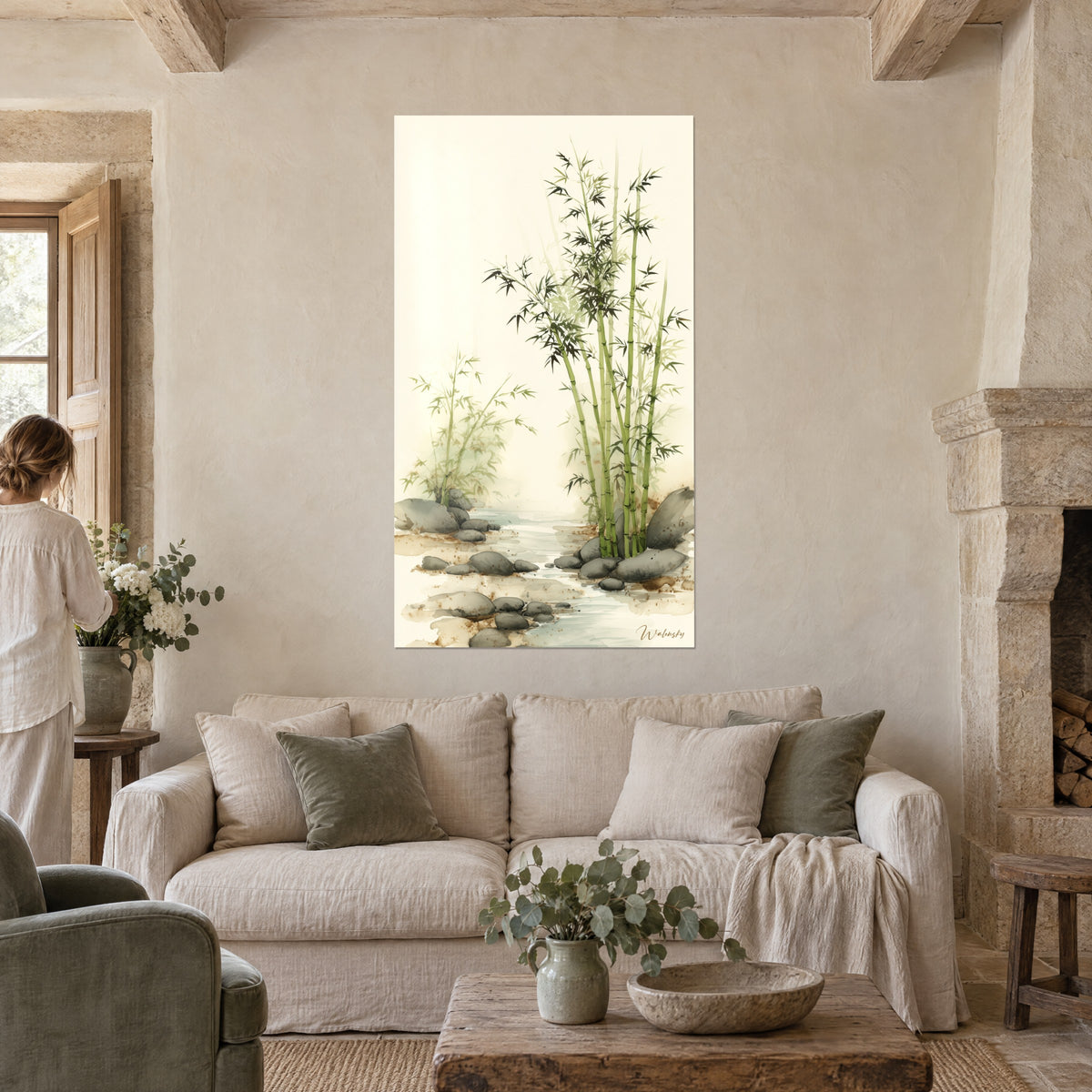 Wall art of green watercolor bamboo on a cream background, gray pebbles and a pale stream, a woman seen from behind, above a sofa in a bright living room