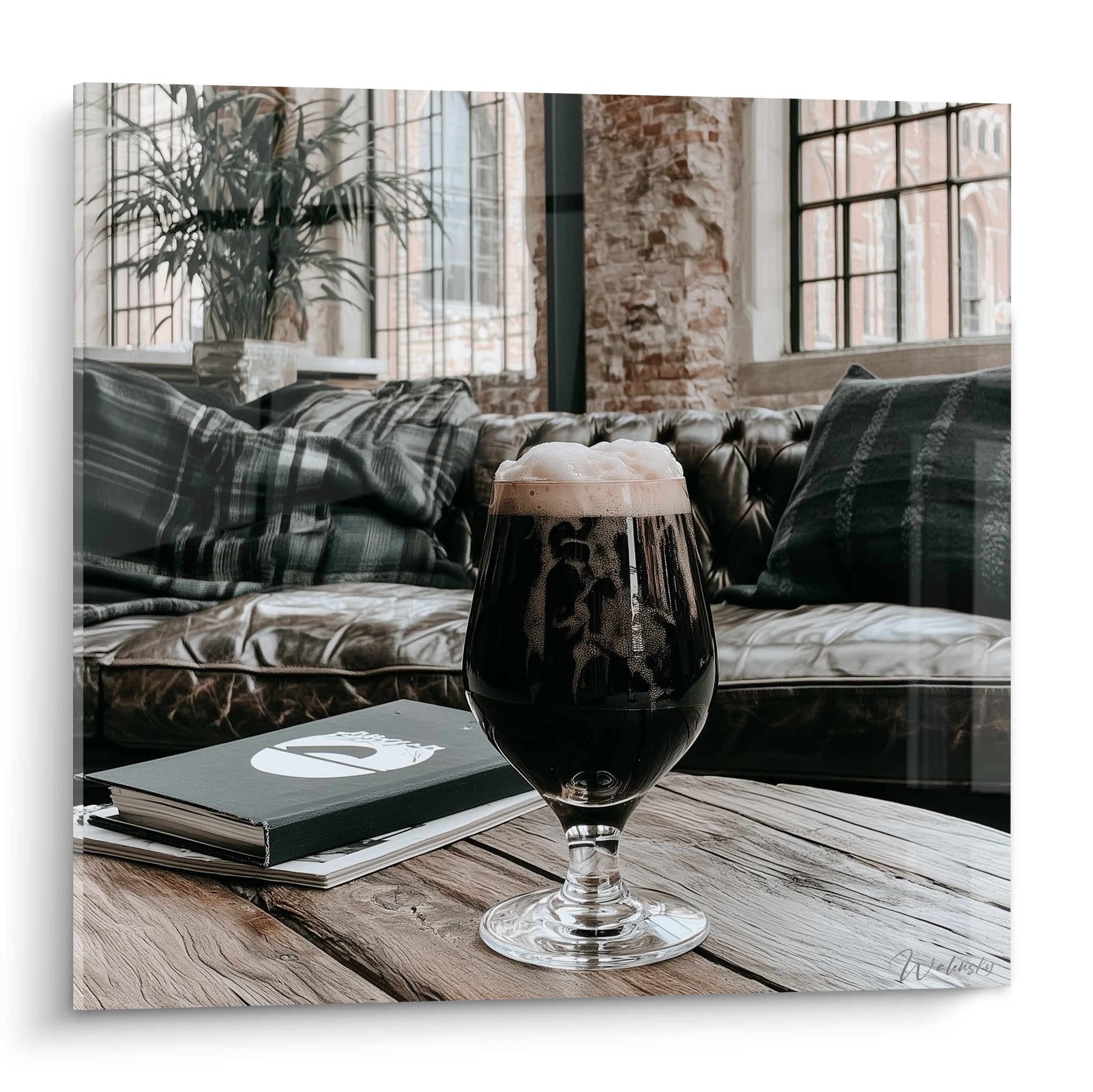 Verre de bière brune à mousse ivoire posé sur une table en bois, décor industriel briques rouges