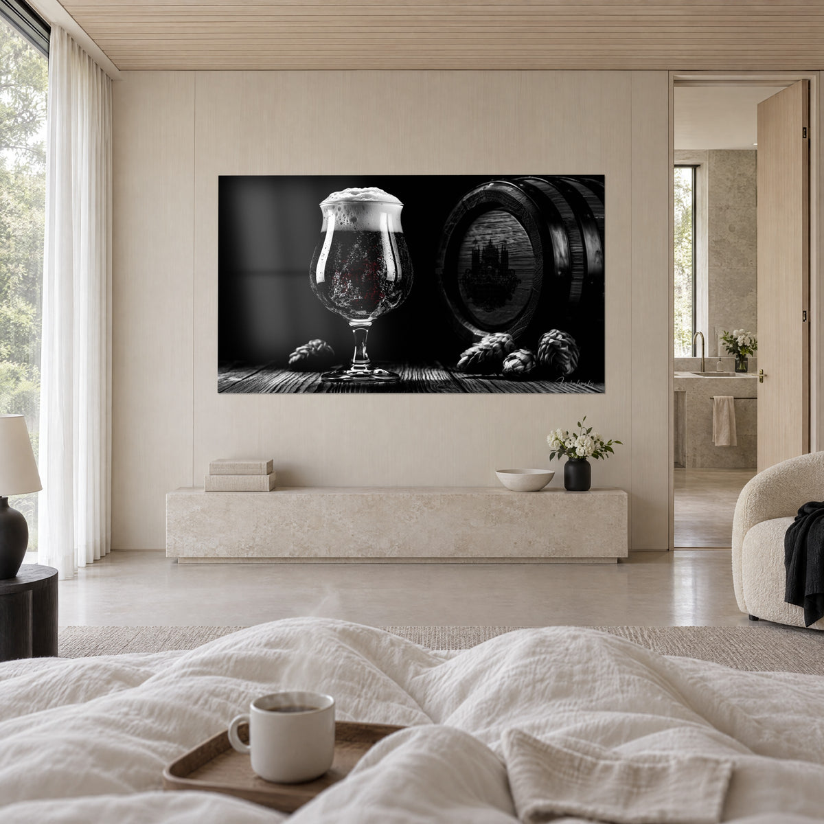 Quadro calice di birra scura con schiuma nevosa, botte incisa con un castello e luppolo in rilievo, in bianco e nero, sopra un letto in una camera luminosa