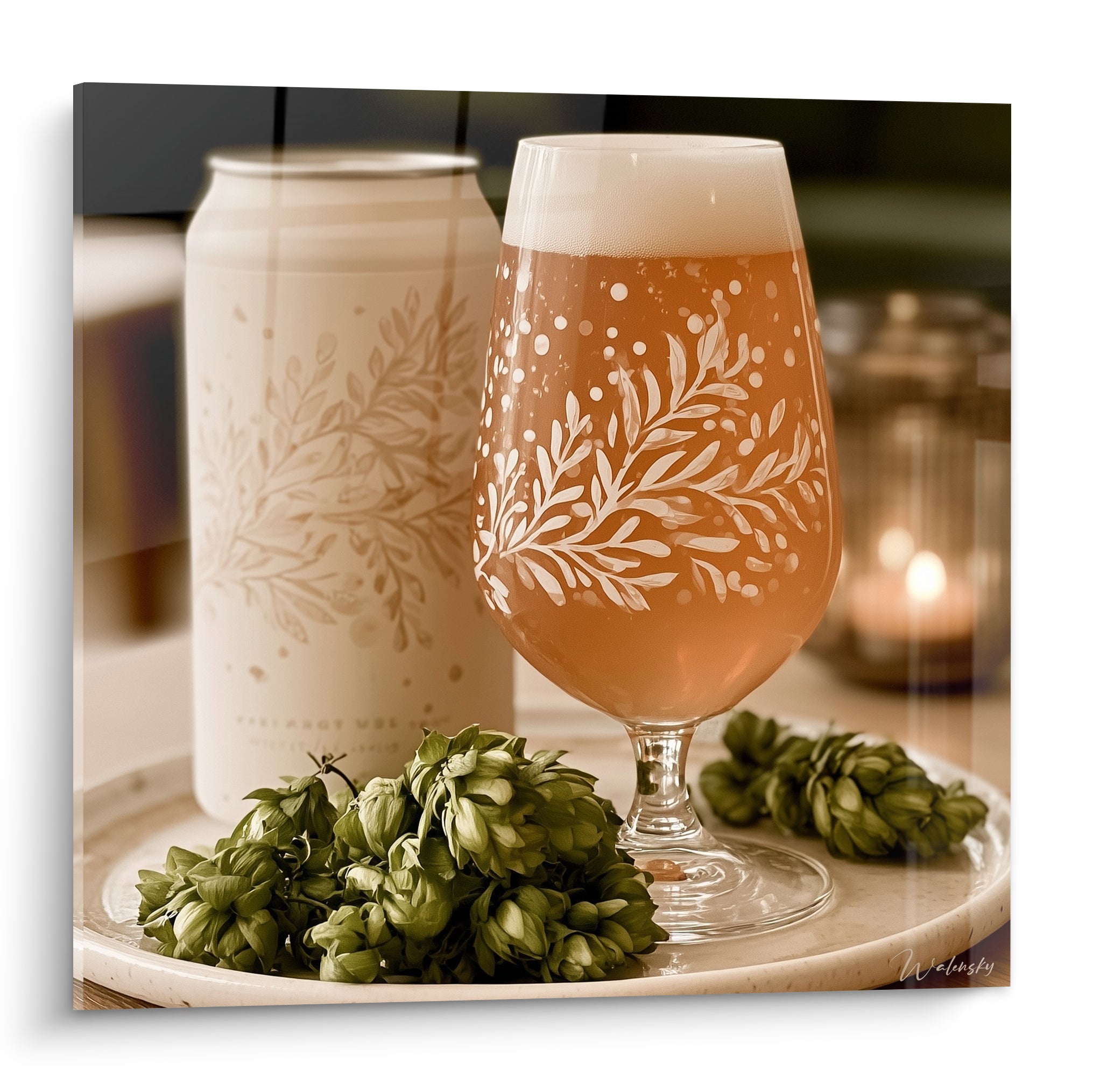 Verre de bière ambrée orné de motifs floraux blancs, entouré de houblon vert olive